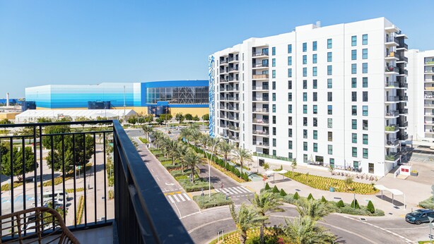 Un grand hôtel à plusieurs étages, doté d’un parking et offrant une vue sur un immeuble bleu en arrière-plan.