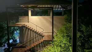 Un escalier moderne avec une balustrade en verre menant à un espace extérieur couvert.