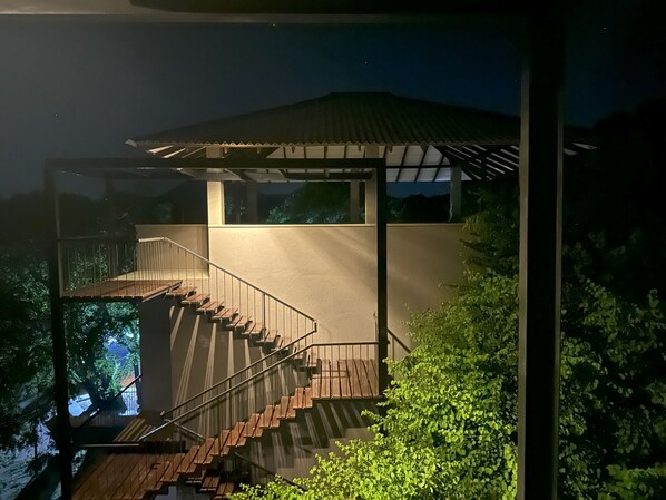 Un escalier moderne avec une balustrade en verre menant à un espace extérieur couvert.