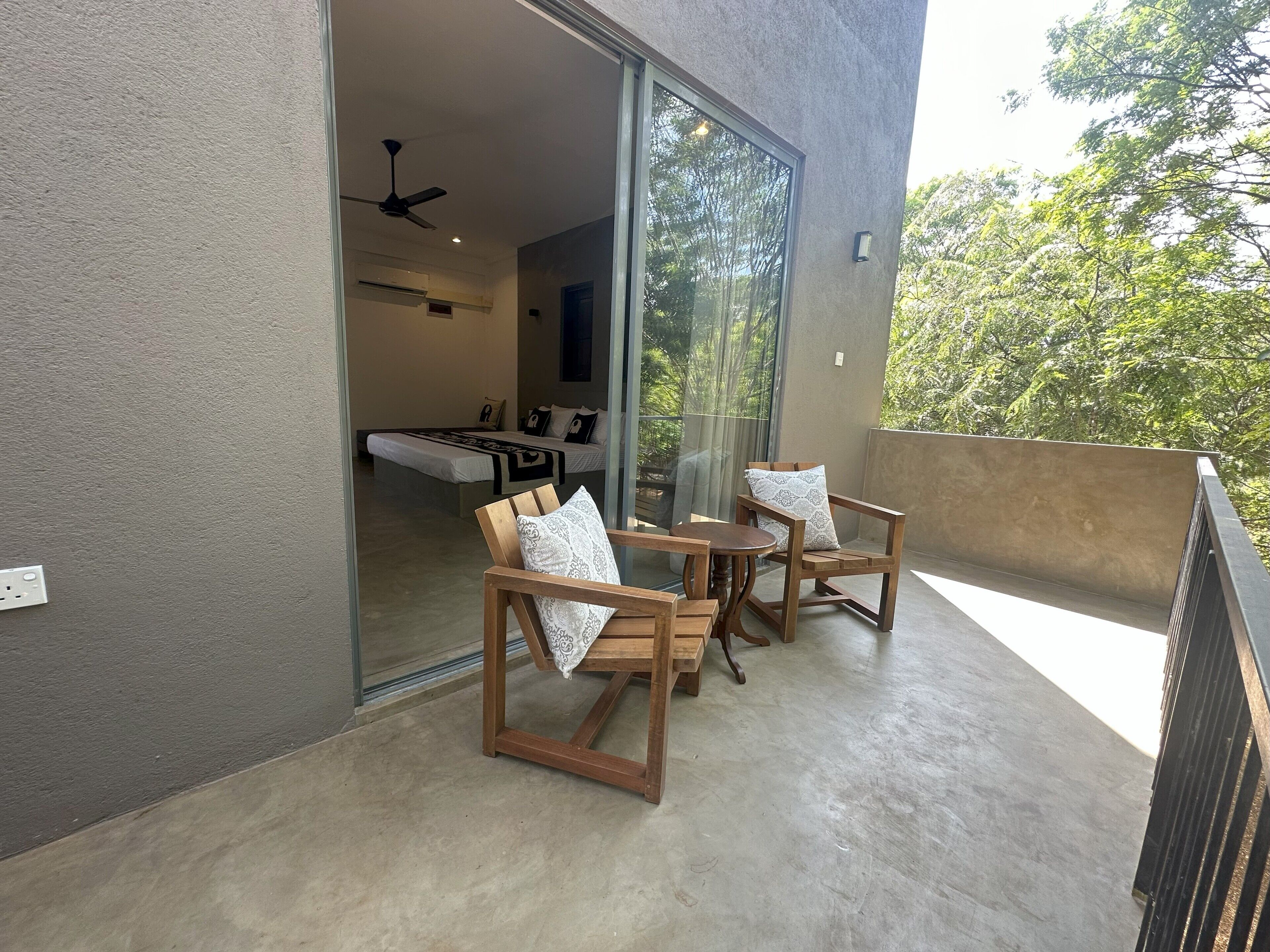 Un balcón con mobiliario de madera y una puerta de cristal que da a un dormitorio.