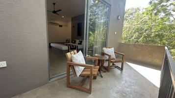 Un balcón con mobiliario de madera y una puerta de cristal que da a un dormitorio.