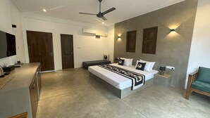 A modern bedroom with a large bed, a ceiling fan, and a TV on a cabinet. - The Den at Yala  (Kataragama)