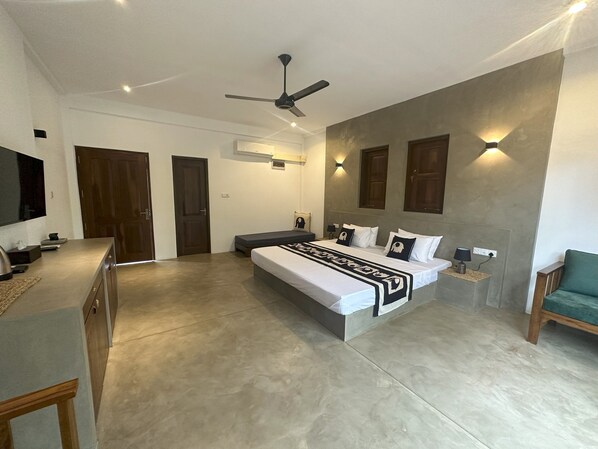 A modern bedroom with a large bed, a ceiling fan, and a TV on a cabinet. - The Den at Yala  (Kataragama)