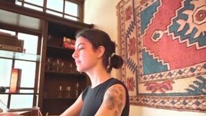 A room with a wooden bookshelf, a patterned wall hanging, and a window with blinds. - Casa Quixote (Braga)
