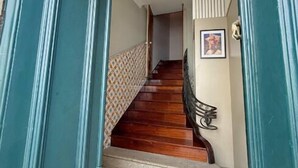 A staircase with wooden steps and a blue mat at the bottom. - Casa Quixote (Braga)