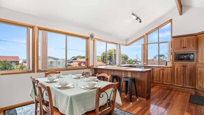 A spacious kitchen with large windows, wooden cabinets, and a dining area set for four.