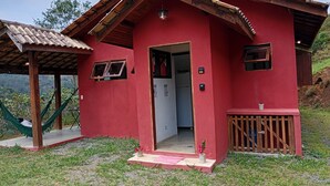 Un piccolo edificio rosso con un portico in legno e un'amaca.