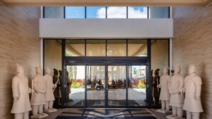 A modern entrance with glass doors, surrounded by stone statues, and a sign reading "Magic Village Views". - 4 Bedrooms / 4.5 Bathrooms/ Magic Village (7566BD) (Kissimmee)