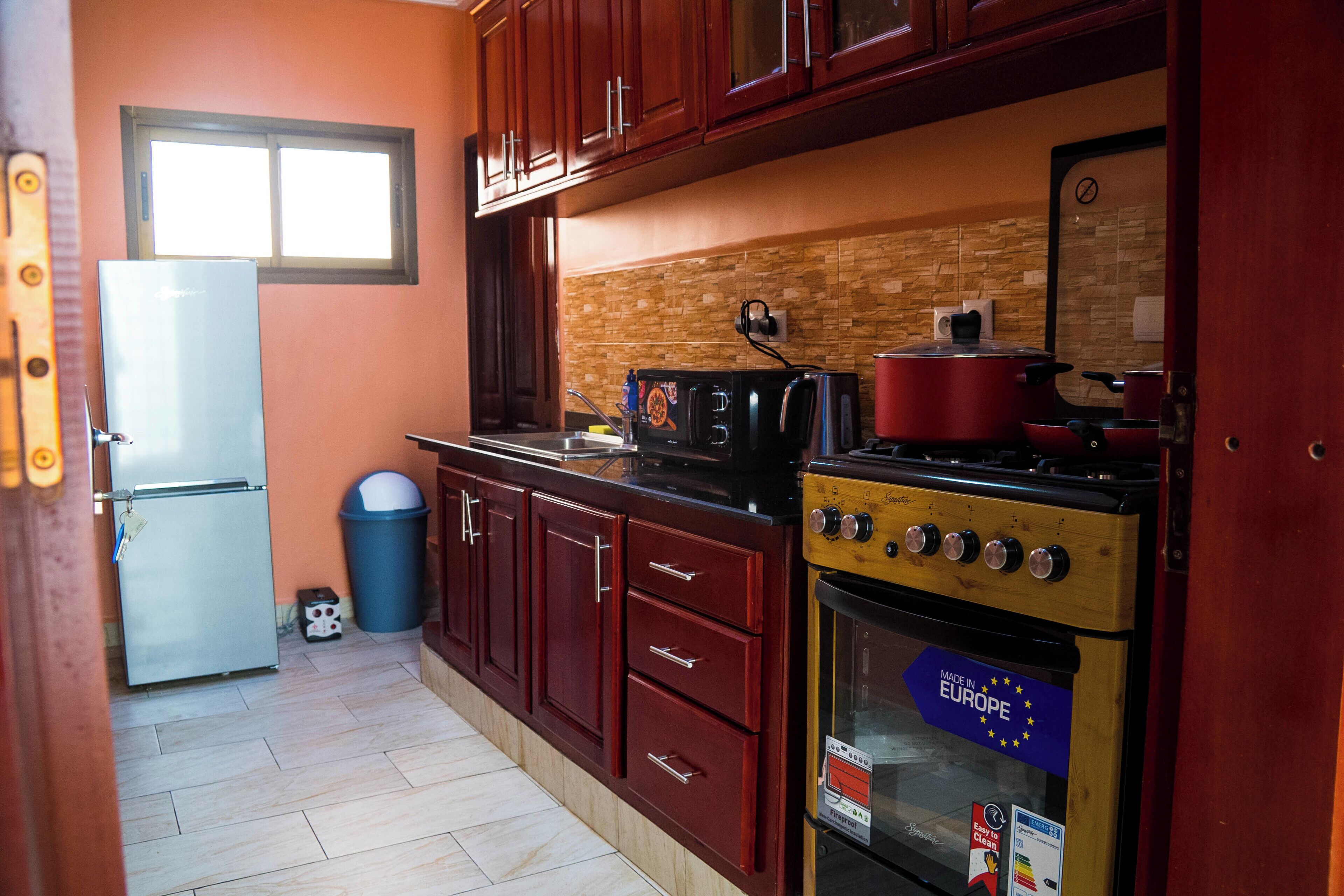Una cocina compacta con refrigerador, estufa y gabinetes de madera.