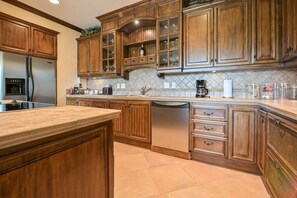 A kitchen with wooden cabinets, a stainless steel refrigerator, a dishwasher, and a tiled backsplash.