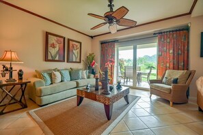 Ein Wohnzimmer mit einer Couch, Sesseln, einem Couchtisch, einer Lampe und einem Deckenventilator.