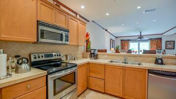 Una cocina moderna con armarios de madera, electrodomésticos de acero inoxidable y un amplio ventanal con cortinas.