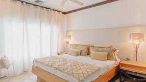Un dormitorio con cama de madera, ropa de cama blanca, una mesita de noche con lámpara y una silla.