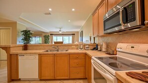 Una cocina moderna con armarios de madera, lavavajillas, microondas, estufa y pileta.