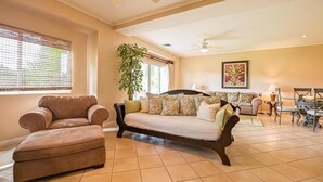Una sala de estar con sofá, reposapiés y una zona comedor con mesa y sillas.