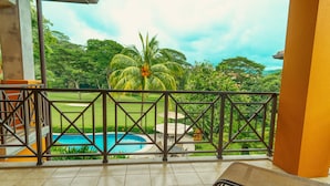 A balcony with a view of a swimming pool, palm trees, and a grassy area. - CR Luxury Veranda 7B 2 Bdrm (Jacó)