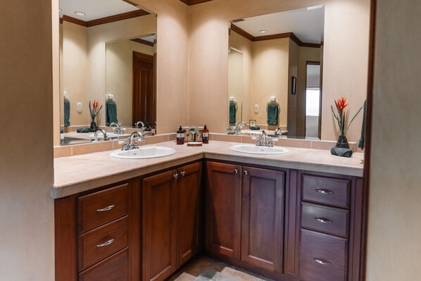Un baño moderno con dos lavabos, armarios de madera y un espejo grande.