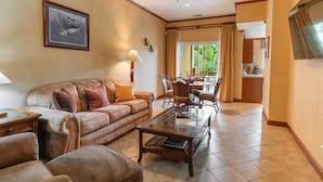A living room with a leather sofa, a glass coffee table, and a dining area with a table and chairs. - CR Luxury Veranda 7B 2 Bdrm (Jacó)