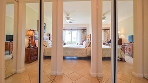 Quarto com duas camas, um ventilador de teto e uma janela grande.