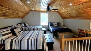 A cozy attic bedroom with two beds, a ceiling fan, and a small table. - Great Lake Haven between Pentwater and Silver Lake (Mears)