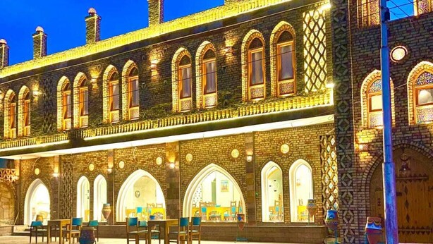 A historic building with arched windows and a courtyard with tables and chairs. - New Abusimble Hotel (Abu Simbel)