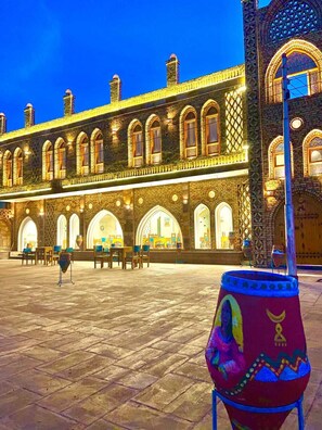 A historic building with arched windows and a courtyard with tables and chairs. - New Abusimble Hotel  (Abu Simbel)