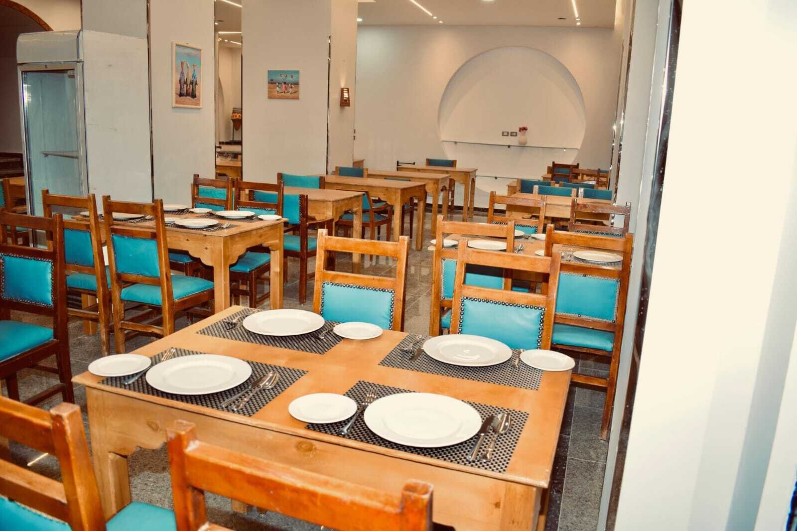 A dining area with multiple tables and chairs, each set with plates and cutlery.
