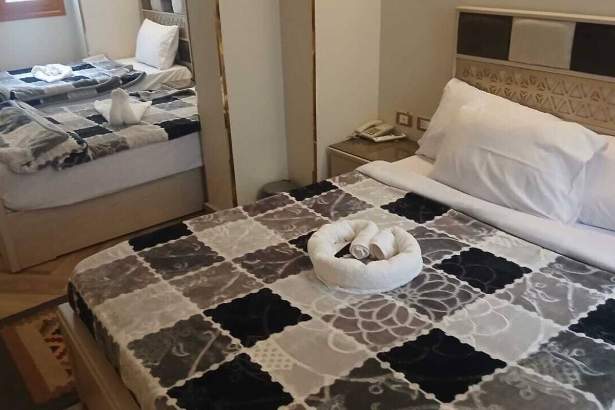A hotel room with a bed, a bedside table with a phone, and a nightstand.