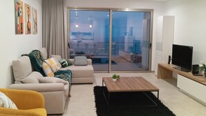A modern living room with a sofa, coffee table, and a TV on a wooden stand. - Holiday House Caetano (PONTA DO SOL)