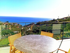 Terraço com mesa e cadeiras com vista para o litoral.