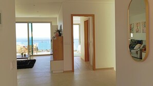 A spacious living area with a view of the sea, a balcony with outdoor furniture, and a modern interior design. - Holiday House Caetano (PONTA DO SOL)