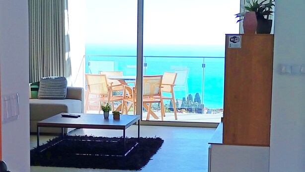 A balcony with a view of the ocean, a sofa, a coffee table, and a plant. - Holiday House Caetano (PONTA DO SOL)