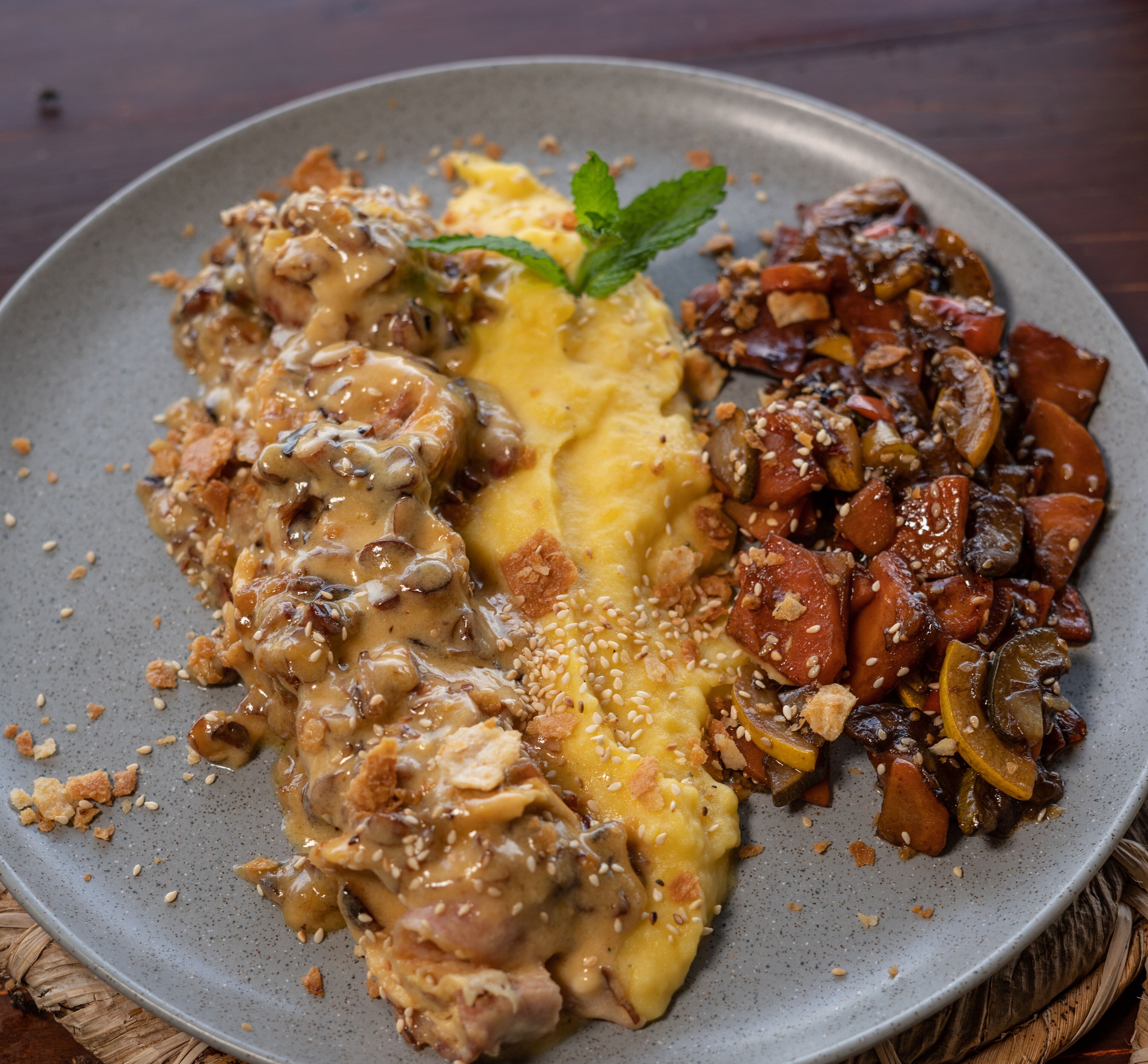 En tallerken mad med forskellige retter, herunder en cremet svamsekauce, kartoffelmos og en portion sauterede grøntsager.