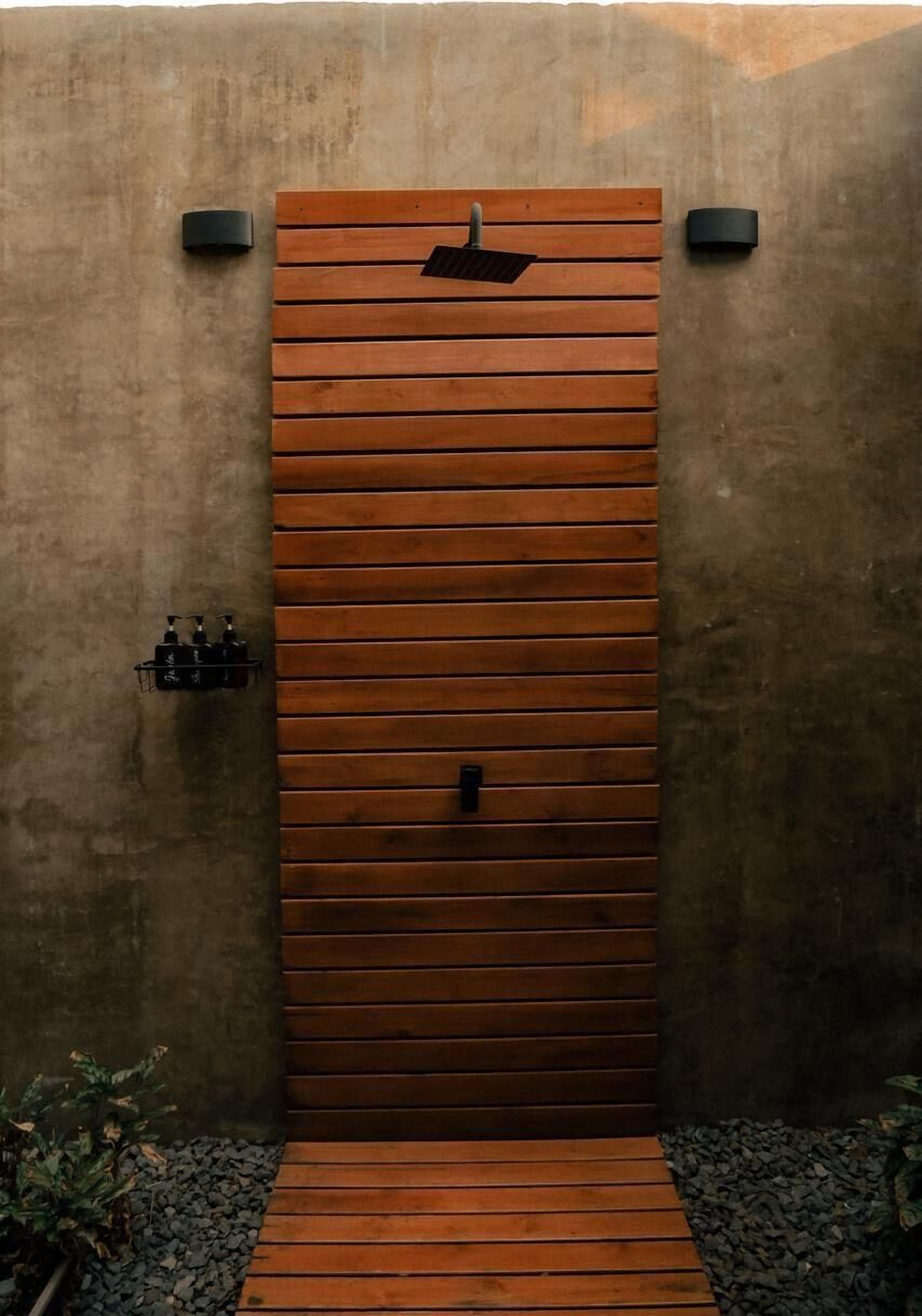 Una puerta de madera con listones horizontales, un escalón que la precede y dos apliques de luz a cada lado.