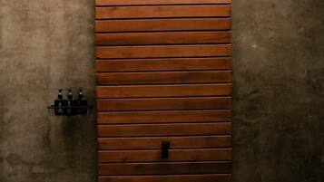 Una puerta de madera con listones horizontales, un escalón que la precede y dos apliques de luz a cada lado.