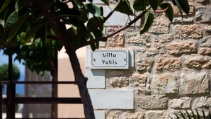 En stenmur med en skylt som visar texten ”Villa Takis”.