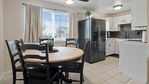 A modern kitchen with a dining area, including a round table with chairs, a ceiling fan, and a refrigerator. - Casamor - Home in Richland (Richland)