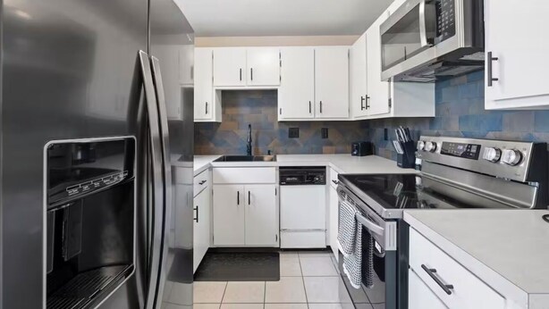 A modern kitchen with white cabinets, a stainless steel refrigerator, a built-in oven, and a microwave. - Casamor - Home in Richland (Richland)