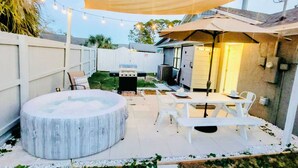 An outdoor patio with a round seating area, white tables, and a canopy providing shade. - Stunning 4BD Jacuzzi - 4 Min To Beach Panama City (Panama City Beach)