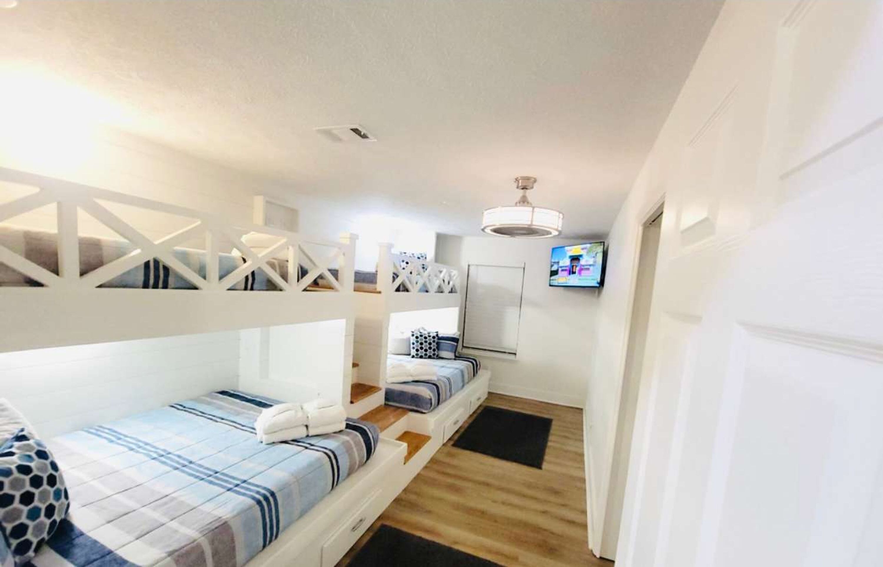 A compact bedroom with bunk beds, a TV, and a ceiling fan.