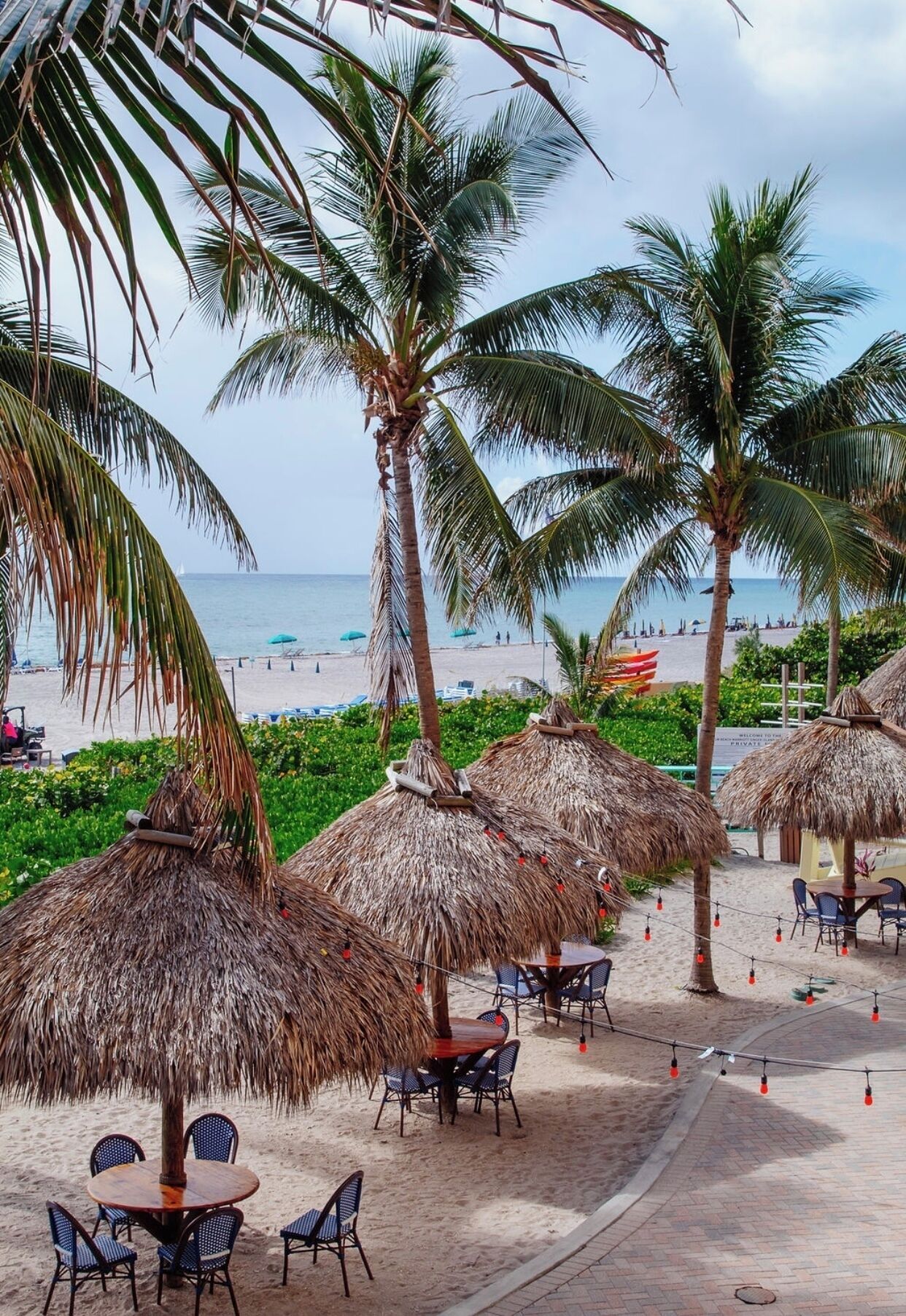 A beachside resort with thatched umbrellas, beach chairs, and a view of the ocean.