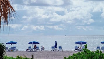 Une plage avec des parasols bleus et des chaises longues.