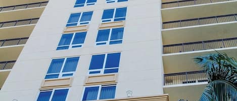 A tall, multi-story hotel with a beige facade, large windows, and balconies.