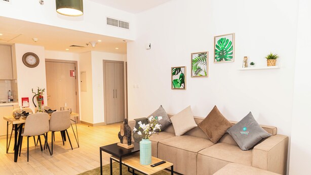 A modern living room with a sofa, coffee table, and dining area. - Bloomfields Stylish 1BR in Waters Edge (Abu Dhabi)