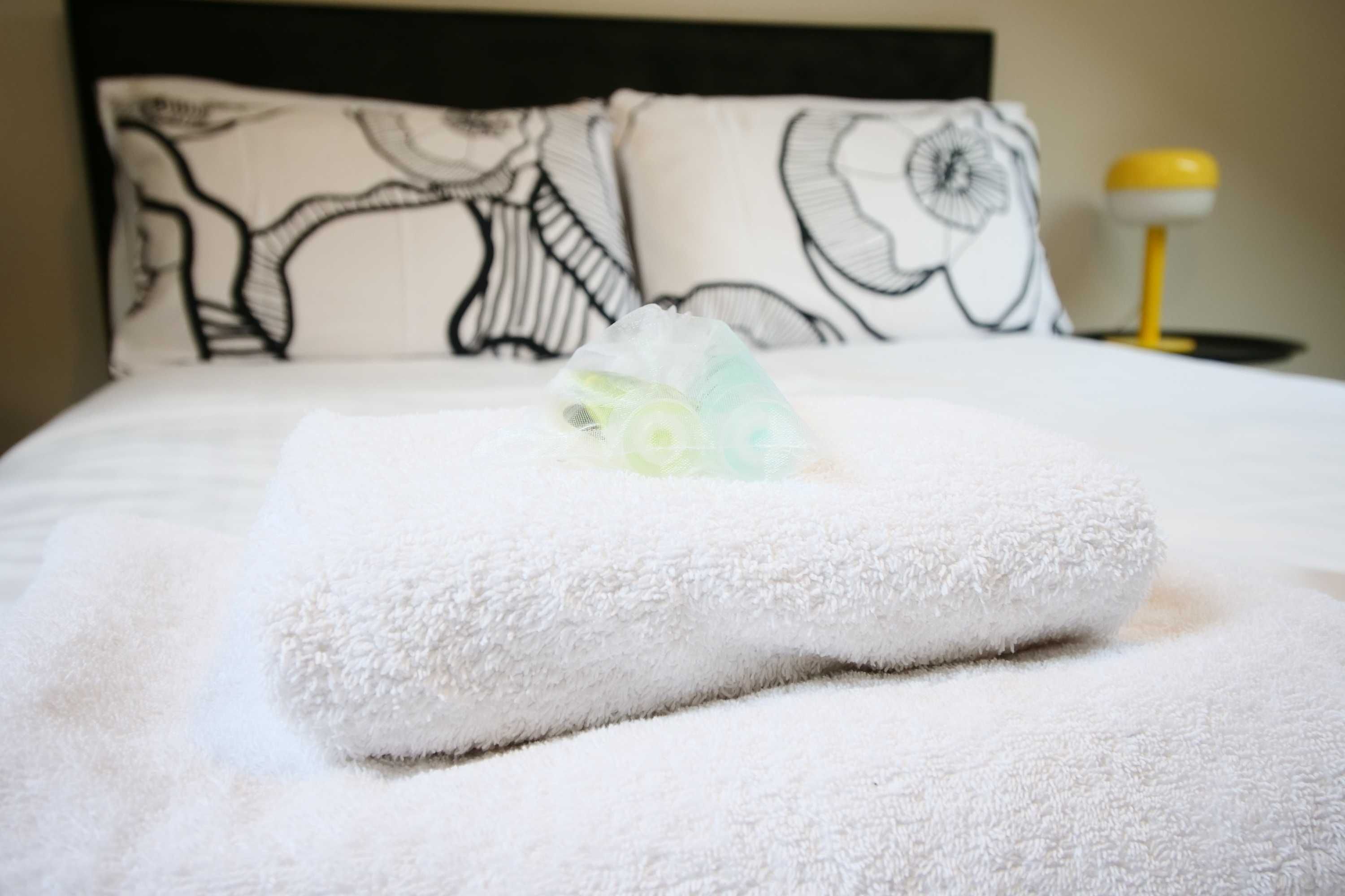 A neatly made bed with a white towel and a folded towel on top.