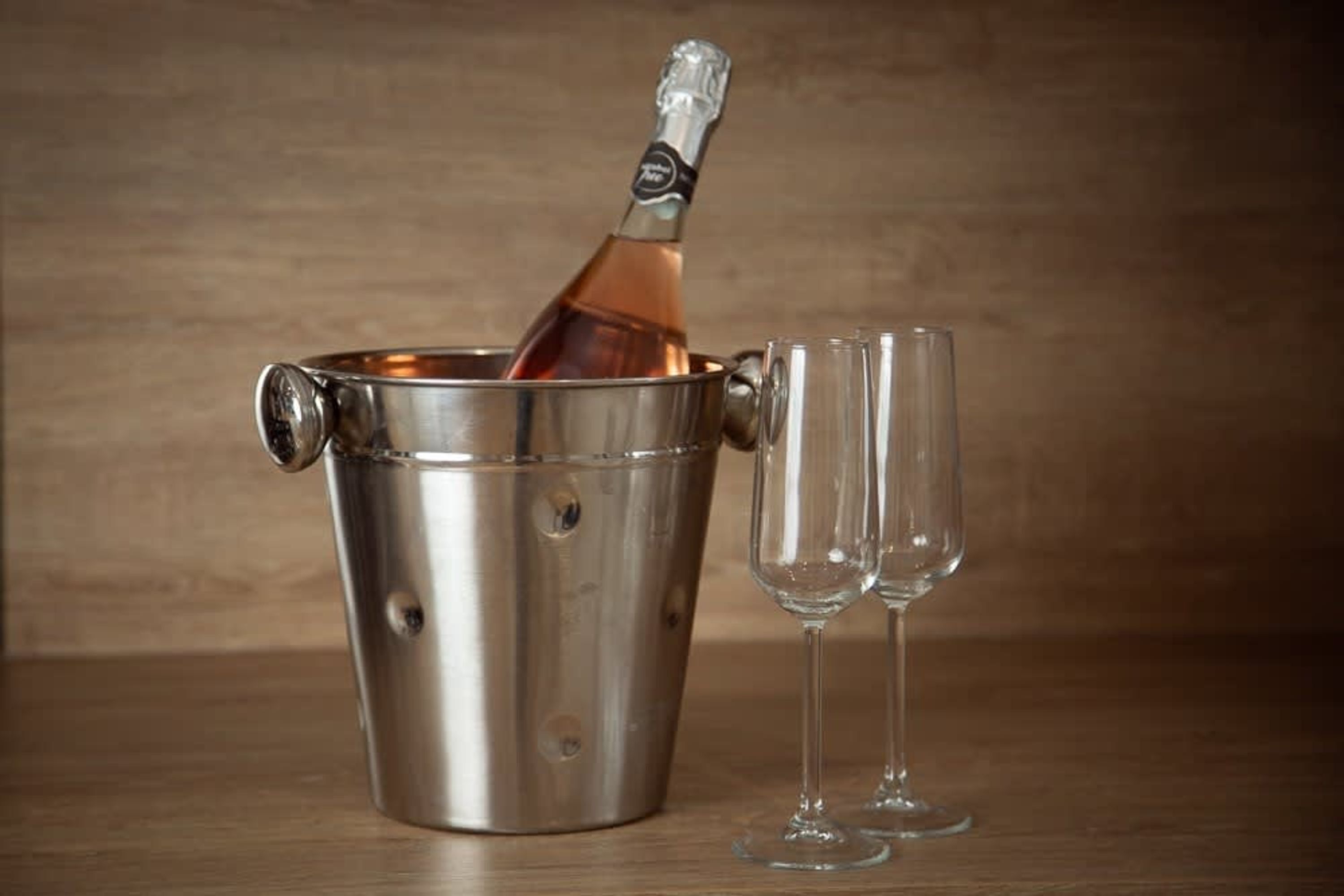 Un seau à champagne en métal, avec une bouteille et deux verres vides.