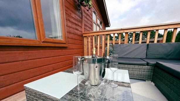 Eine Holzdielen-Terrasse mit einem Glastisch, zwei Weingläsern und einem Champagnerkübel.