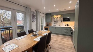 Una cocina moderna con armarios grises, una mesa de comedor de madera con sillas y un gran reloj de pared.