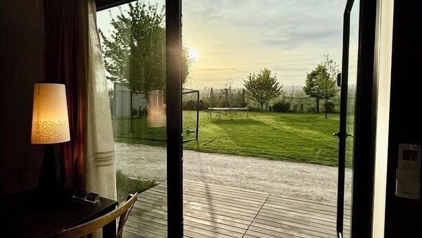 A room with a large sliding glass door leading to a patio with a grassy lawn and a wooden deck. - Memento Agriturismo (Cervia)