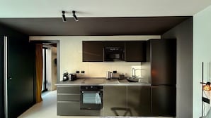 A modern kitchen with built-in appliances, a flat-screen TV, and a dining area with a table and chairs. - Memento Agriturismo (Cervia)